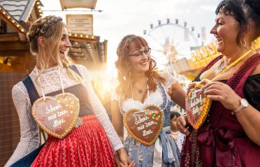 Group of friends in national costume or Dirndl at the Dult, Oktoberfest laugh and have fun at germany, Schenk mir dein Herz (German: Give me your heart) written on gingerbreads souvenir heart : Stock Photo or Stock Video Download rcfotostock photos, images and assets rcfotostock | RC Photo Stock.: