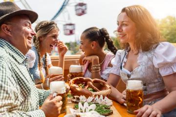 Group of friends in traditional Bavarian outfits laughing and toasting with beer mugs at a vibrant Oktoberfest or dult in germany- Stock Photo or Stock Video of rcfotostock | RC Photo Stock