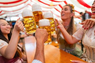 group of happy friends toasting with large mugs of beer at Oktoberfest, smiling and celebrating under colorful festival tent in munich germany : Stock Photo or Stock Video Download rcfotostock photos, images and assets rcfotostock | RC Photo Stock.: