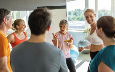 Group of people discussing with a female trainer about nutritional advice holding a banana in a gym setting : Stock Photo or Stock Video Download rcfotostock photos, images and assets rcfotostock | RC Photo Stock.: