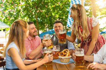 Group of people in proper Tracht toasting and drinking in Bavarian beer garden or oktoberfest at summer in germany- Stock Photo or Stock Video of rcfotostock | RC Photo Stock