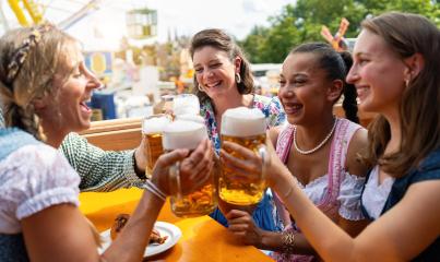 Group of women in traditional tracht dresses toasting with beer mugs at oktoberfest in germany festival, amusement park in background : Stock Photo or Stock Video Download rcfotostock photos, images and assets rcfotostock | RC Photo Stock.: