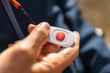 hand activating a red SOS emergency button on a safety device, attached to a jacket with an orange lanyard. Dementia retirement home concept image- Stock Photo or Stock Video of rcfotostock | RC Photo Stock