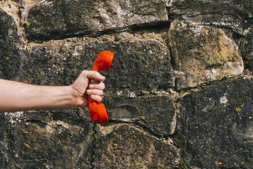 hand holding a red telephone receiver against a stone wall- Stock Photo or Stock Video of rcfotostock | RC Photo Stock