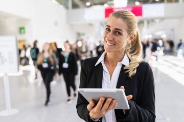 happy businesswoman at a trade fair holding tablet- Stock Photo or Stock Video of rcfotostock | RC Photo Stock