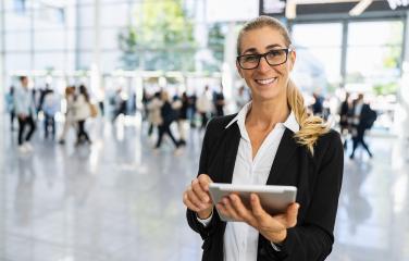 happy businesswoman with glasses at a trade fair holding tablet- Stock Photo or Stock Video of rcfotostock | RC Photo Stock