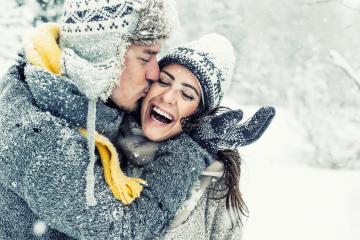 Happy couple embracing in a snowy winter setting, wearing cozy sweaters, scarves, and hats, with the man kissing the woman on the cheek as they laugh in a joyful, snowy moment : Stock Photo or Stock Video Download rcfotostock photos, images and assets rcfotostock | RC Photo Stock.: