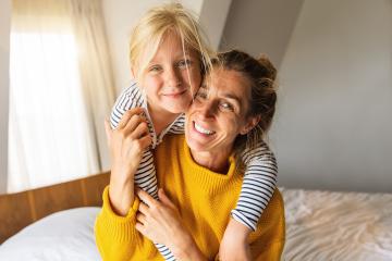 Happy daughter giving mother piggybacking smiling at camera. Good time at home concept image : Stock Photo or Stock Video Download rcfotostock photos, images and assets rcfotostock | RC Photo Stock.: