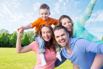 Happy family of four enjoying outdoor fun in a sunny park, with the young boy on the mother’s shoulders and the girl playing on the father’s back, all smiling and laughing in a vibrant setting : Stock Photo or Stock Video Download rcfotostock photos, images and assets rcfotostock | RC Photo Stock.: