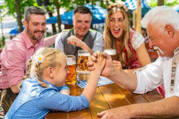 Happy family practicing the high art of arm wrestling in a beer garden ir oktoberste- Stock Photo or Stock Video of rcfotostock | RC Photo Stock