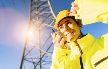 Happy female Electrical engineer talking in a walkie talkie to control a high voltage electricity pylon. Electrical power lines and towers with bright sun- Stock Photo or Stock Video of rcfotostock | RC Photo Stock