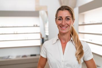 Happy optician in white blouse at eyeglass shop. Glasses and she- Stock Photo or Stock Video of rcfotostock | RC Photo Stock