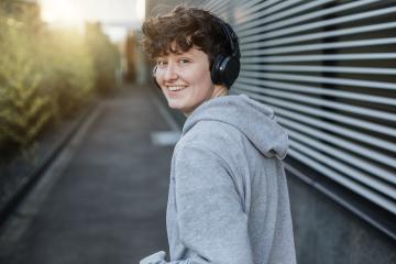 Happy person in gray sweater is jogging on the street and looks happy. Portrait of a young jogger in an urban space.- Stock Photo or Stock Video of rcfotostock | RC Photo Stock