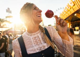 Happy woman eating candy apple on a Bavarian fair or oktoberfest or duld in Dirndl at germany  : Stock Photo or Stock Video Download rcfotostock photos, images and assets rcfotostock | RC Photo Stock.: