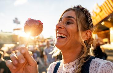 Happy woman eating candy apple on a Bavarian fair or oktoberfest or duld in national costume or Dirndl in germany  : Stock Photo or Stock Video Download rcfotostock photos, images and assets rcfotostock | RC Photo Stock.:
