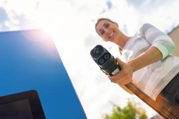 Happy woman holding a DC CCS2 EV charging connector on a 300KW H- Stock Photo or Stock Video of rcfotostock | RC Photo Stock