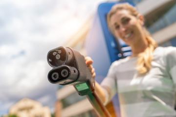 Happy woman holding a DC CCS2 EV charging connector on Hyperchar : Stock Photo or Stock Video Download rcfotostock photos, images and assets rcfotostock | RC Photo Stock.: