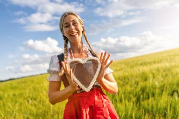 Happy woman in Bavarian dirndl holding a gingerbread heart celebrating Oktoberfest, with copyspace for your individual text.- Stock Photo or Stock Video of rcfotostock | RC Photo Stock
