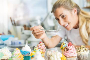 happy women in pastry bakery as confectioner sprinkles powdered sugar in a colander as topping on a colorful muffin : Stock Photo or Stock Video Download rcfotostock photos, images and assets rcfotostock | RC Photo Stock.: