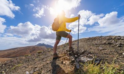 Hiker in yellow jacket climbing a mountain path against a sunny, cloud-filled sky : Stock Photo or Stock Video Download rcfotostock photos, images and assets rcfotostock | RC Photo Stock.: