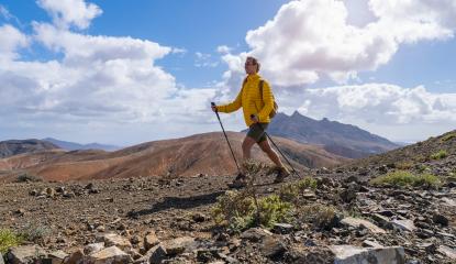 Hiker in yellow jacket walking on mountain trail with cloudy sky and peak in distance : Stock Photo or Stock Video Download rcfotostock photos, images and assets rcfotostock | RC Photo Stock.:
