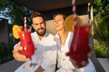 joyful couple in white spa robes enjoying red cocktails at a wellness resort- Stock Photo or Stock Video of rcfotostock | RC Photo Stock