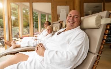 joyful father in the foreground, smiling with his family relaxing in white robes in a bright spa lounge- Stock Photo or Stock Video of rcfotostock | RC Photo Stock