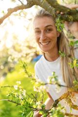 Joyful mature woman smiling, peeking through lush apple tree branches in spring : Stock Photo or Stock Video Download rcfotostock photos, images and assets rcfotostock | RC Photo Stock.: