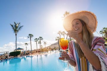 Joyful woman in a straw hat enjoying a colorful cocktail by a sunny poolside with palm trees in the background at a spanish hotel : Stock Photo or Stock Video Download rcfotostock photos, images and assets rcfotostock | RC Photo Stock.: