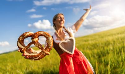 Joyful woman in Bavarian tracht with a gingerbread heart, holding a pretzel in a wheat field celebrating Oktoberfest or dult festival in munich. : Stock Photo or Stock Video Download rcfotostock photos, images and assets rcfotostock | RC Photo Stock.: