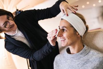 make up assistant cleans with a cleaning pad make up from a face of a happy model for a photoshoot on location.- Stock Photo or Stock Video of rcfotostock | RC Photo Stock