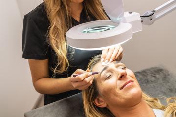 Make-up artist plucks eyebrows with tweezers to a woman. Beautiful thick eyebrows in spa center or cosmetology salon. Makeup and Cosmetology concept image : Stock Photo or Stock Video Download rcfotostock photos, images and assets rcfotostock | RC Photo Stock.: