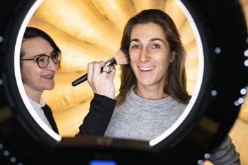 makeup artist powders a models face posing at camera through ring light lamp. Photo shooting with ring light or movie set location- Stock Photo or Stock Video of rcfotostock | RC Photo Stock