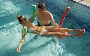 Male trainer using pool noodles to assist a client with rehabilitation exercises in a pool- Stock Photo or Stock Video of rcfotostock | RC Photo Stock