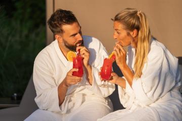 Man and woman in white robes sipping cocktails in golden hour light at spa hotel resort- Stock Photo or Stock Video of rcfotostock | RC Photo Stock
