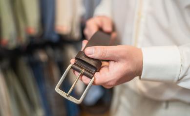 Man holding a brown leather belt with a large silver buckle at a clothing store : Stock Photo or Stock Video Download rcfotostock photos, images and assets rcfotostock | RC Photo Stock.: