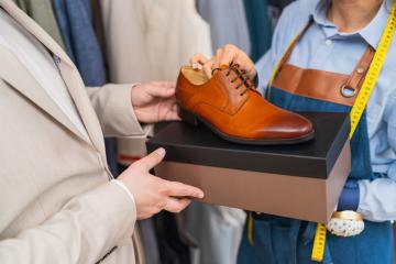 man holding a tan dress shoe above a shoe box with a tailor holding a tape measure : Stock Photo or Stock Video Download rcfotostock photos, images and assets rcfotostock | RC Photo Stock.: