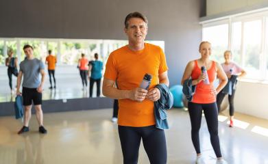 Man in orange shirt holding a water bottle in gym with other people and exercise balls. Teamwork Concept image : Stock Photo or Stock Video Download rcfotostock photos, images and assets rcfotostock | RC Photo Stock.: