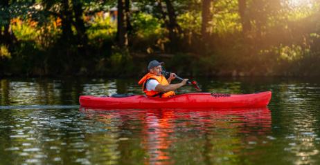 Man kayaking alone in a red kayak on a serene river, surrounded by lush greenery in glowing evening light. Kayak Water Sports concept image- Stock Photo or Stock Video of rcfotostock | RC Photo Stock