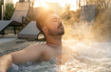 Man relaxing in a hot tub with steam rising around him at sunset at spa resort hotel : Stock Photo or Stock Video Download rcfotostock photos, images and assets rcfotostock | RC Photo Stock.: