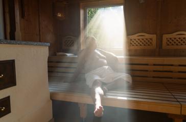 Man sitting in a sauna with light streaming through the window onto his relaxed figure.- Stock Photo or Stock Video of rcfotostock | RC Photo Stock