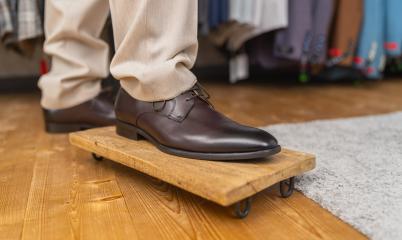 Man trying on brown leather shoes, standing on one foot on a wooden board : Stock Photo or Stock Video Download rcfotostock photos, images and assets rcfotostock | RC Photo Stock.: