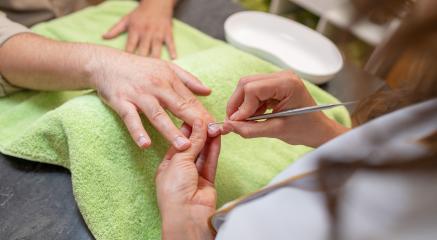 Manicurist performing a manicure, focusing on a client's nails with a cuticle pusher being used over a green towel : Stock Photo or Stock Video Download rcfotostock photos, images and assets rcfotostock | RC Photo Stock.: