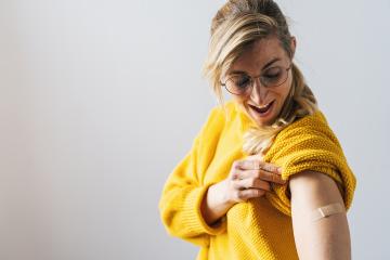 mature woman getting a vaccine injection for Covid-19. Woman holding up her shirt sleeve and showing her arm with Adhesive bandage Plaster after receiving vaccination- Stock Photo or Stock Video of rcfotostock | RC Photo Stock
