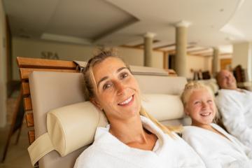 mother and her daughter smiling at the camera, with the father in the background, all relaxing in a spa lounge- Stock Photo or Stock Video of rcfotostock | RC Photo Stock