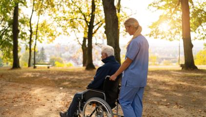 nurse walks with an elderly man in a wheelchair through a sunlit park, surrounded by autumn foliage. nursery home concept image- Stock Photo or Stock Video of rcfotostock | RC Photo Stock