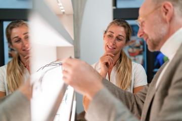 Optician and customer discussing eyeglasses. Looking at shelves with various eyeware in an optical shop.- Stock Photo or Stock Video of rcfotostock | RC Photo Stock