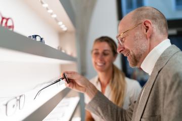 Optician and customer discussing new eyeglasses. Shelves with various frames in an optical shop.- Stock Photo or Stock Video of rcfotostock | RC Photo Stock