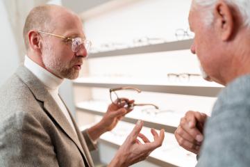 Optician discussing eyeglasses models with elderly client in optical store- Stock Photo or Stock Video of rcfotostock | RC Photo Stock