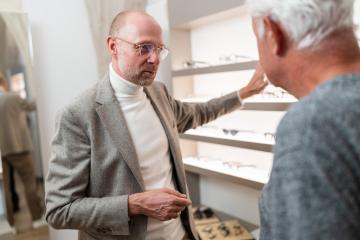 Optician showing eyewear to elderly client in optical store and explaining different eyewear models.- Stock Photo or Stock Video of rcfotostock | RC Photo Stock